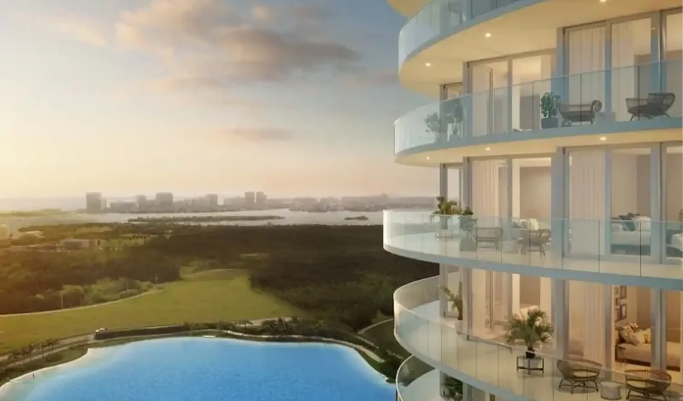 Balcón curvo con vistas a la laguna Crystal Lagoon™ y la bahía de Biscayne desde una torre de lujo en One Park Tower by Turnberry, North Miami.
